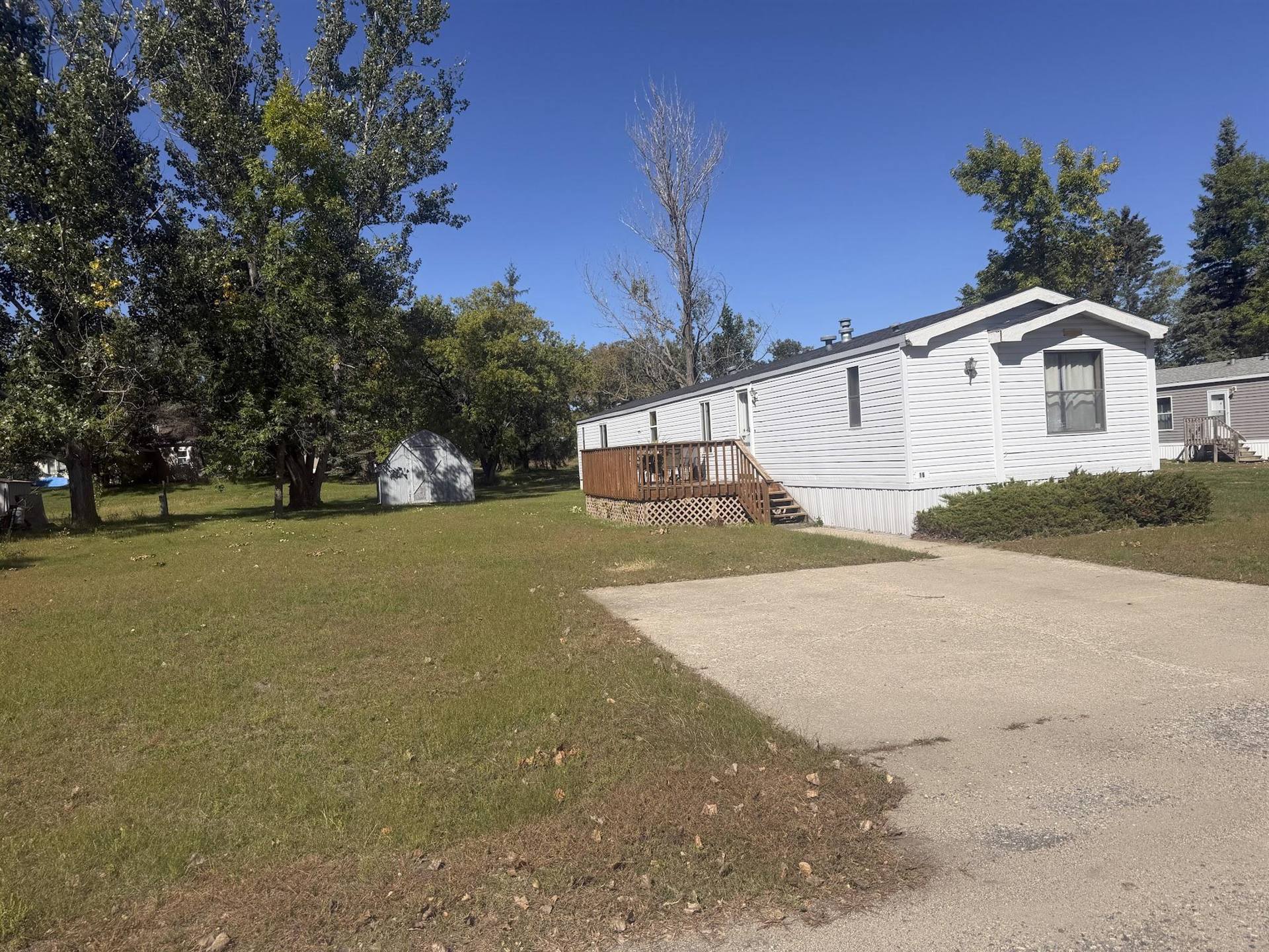 A white home with a wooden deck under a blue sky at Kountry Manor